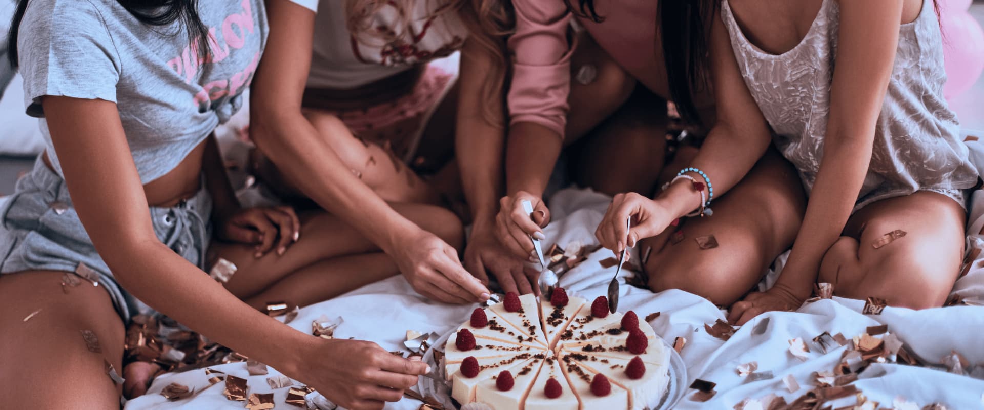 Mulheres sentadas na cama dividindo bolo.